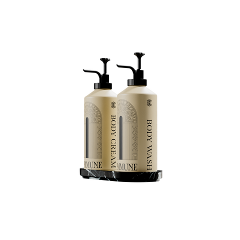 Two cream-colored pump bottles labeled 'BODY CREAM' and 'BODY WASH' with black dispensers, displayed on a black marble tray